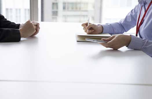 Two people meeting across a desk with documents